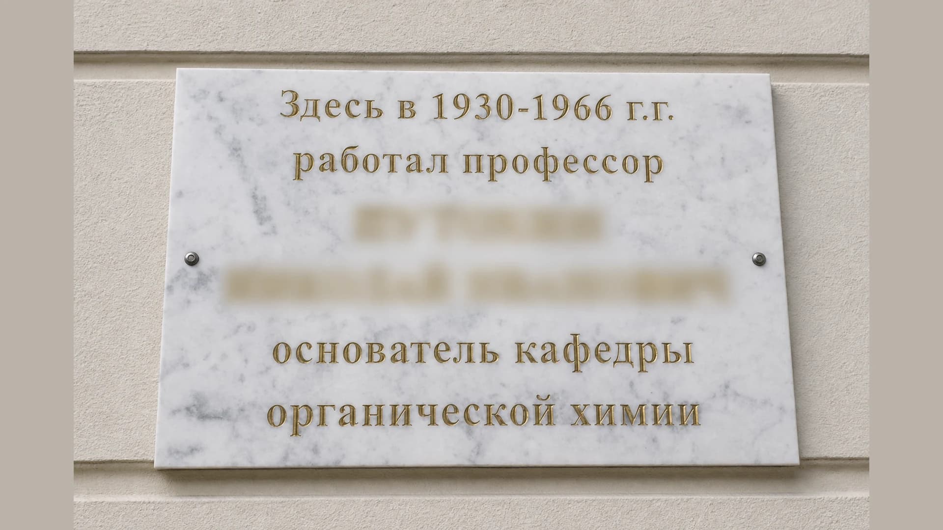 Белая мраморная мемориальная доска с золотой гравировкой на фасаде